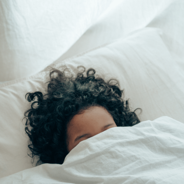 a woman with curly hair laying in bed resting as part of her evening routine