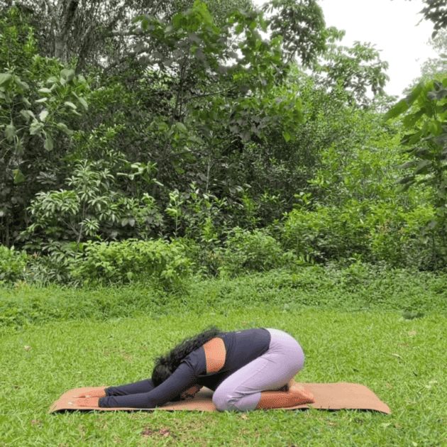 a woman doing yoga at home in a pose called childs pose