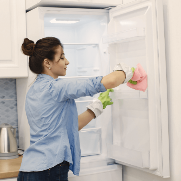 a person using white vinegar spray to clean their fridge